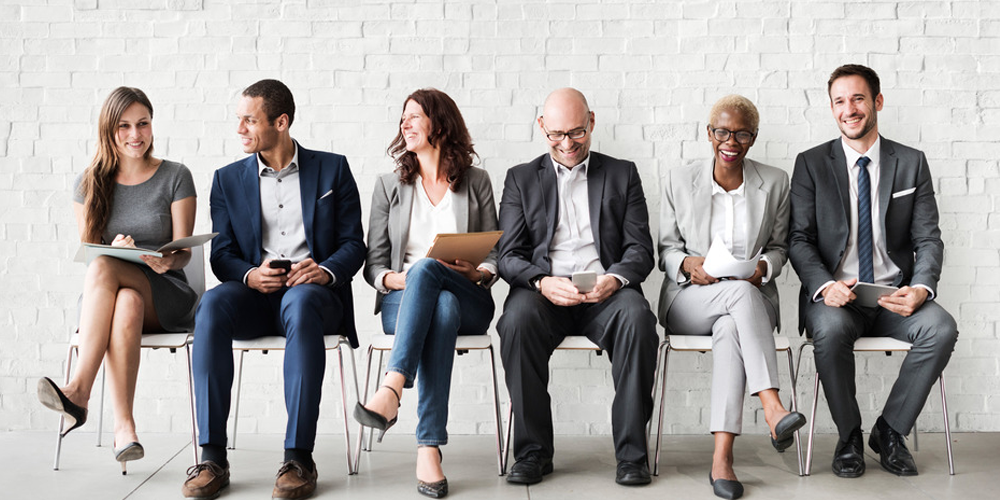 Six professionals sitting on chairs smiling. Aviso Wealth Financial Services